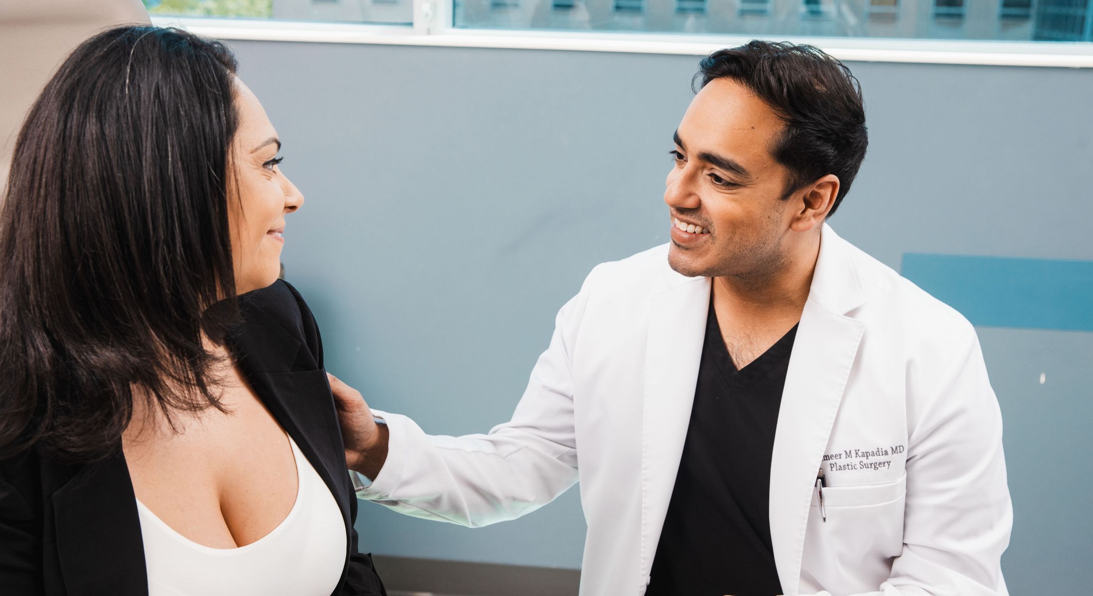 Dr. Kapadia consulting with Mommy Makeover patient in medical setting.