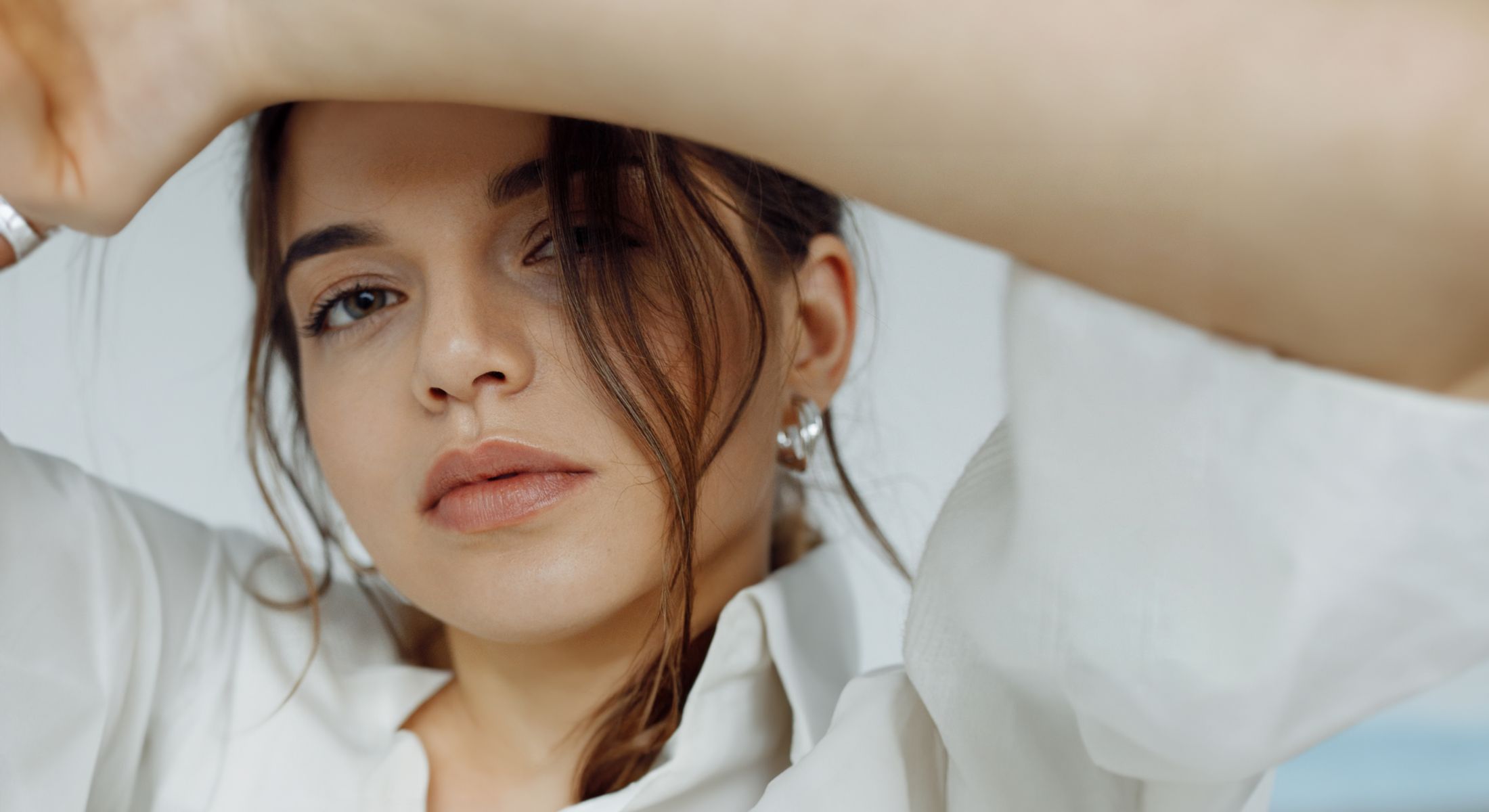 Woman in white shirt posing thoughtfully indoors.