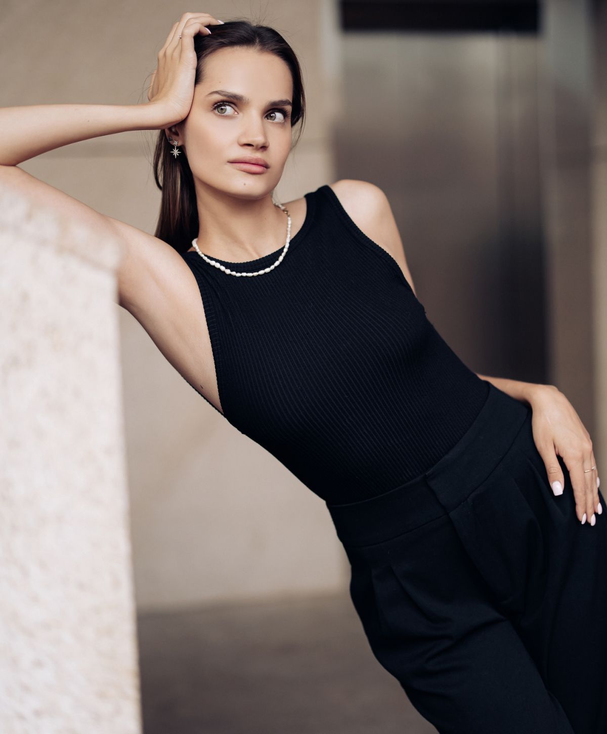 Woman in black outfit posing elegantly indoors.