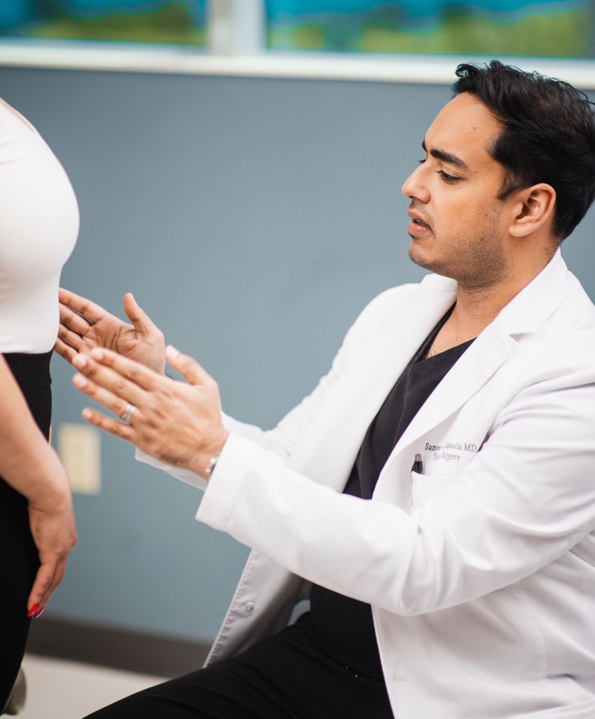 Dr. Kapadia consulting with a Mommy Makeover patient in clinic.