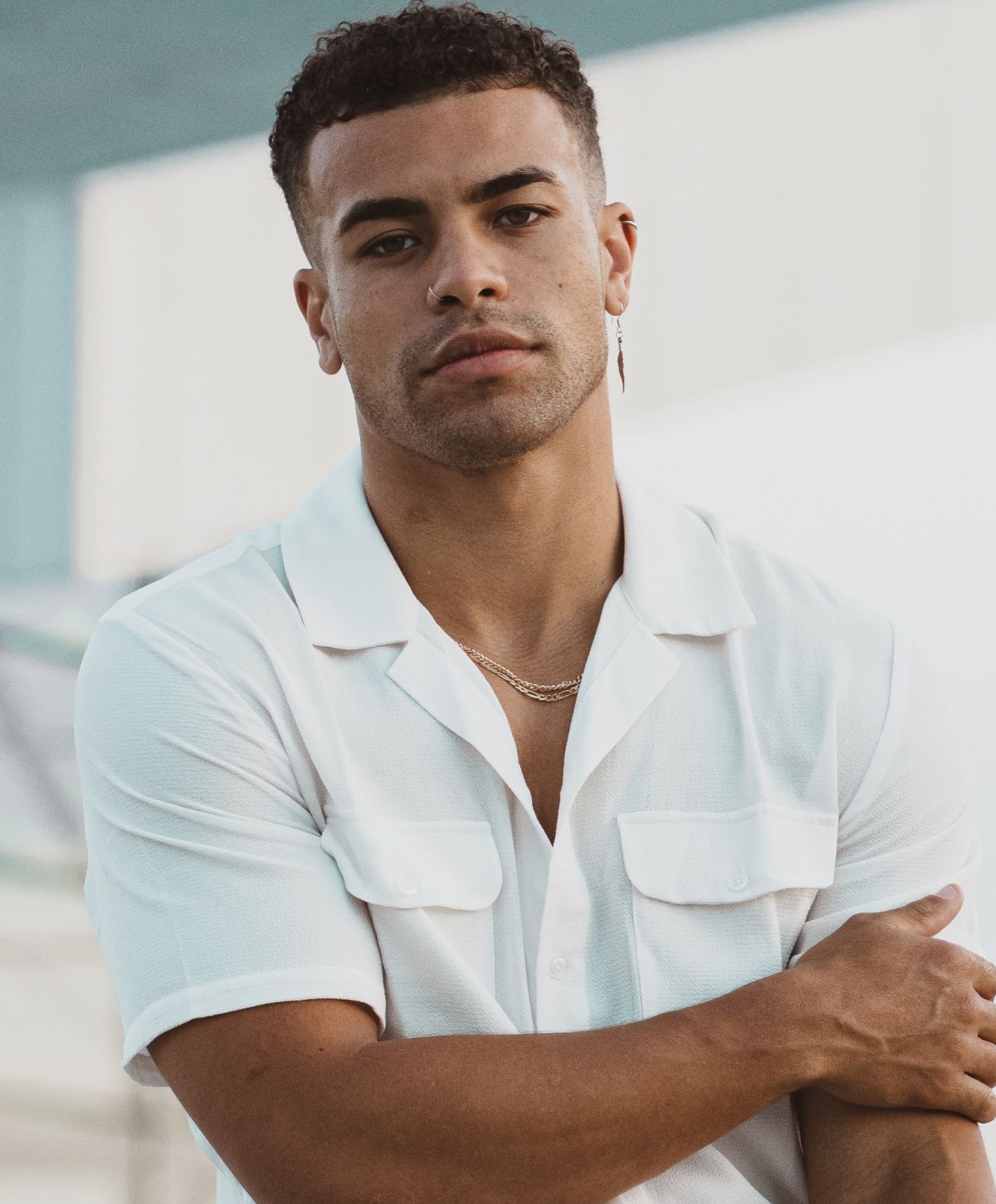 Man in white shirt posing confidently outdoors.