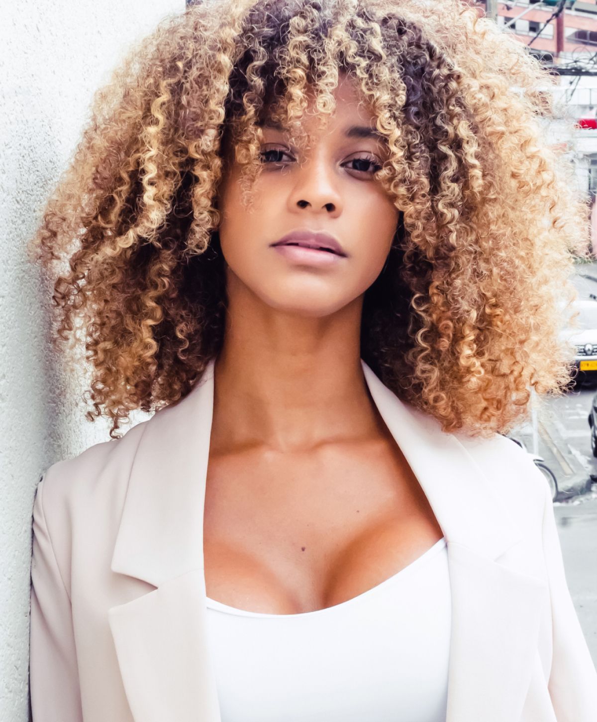 Woman with curly hair in stylish outfit.